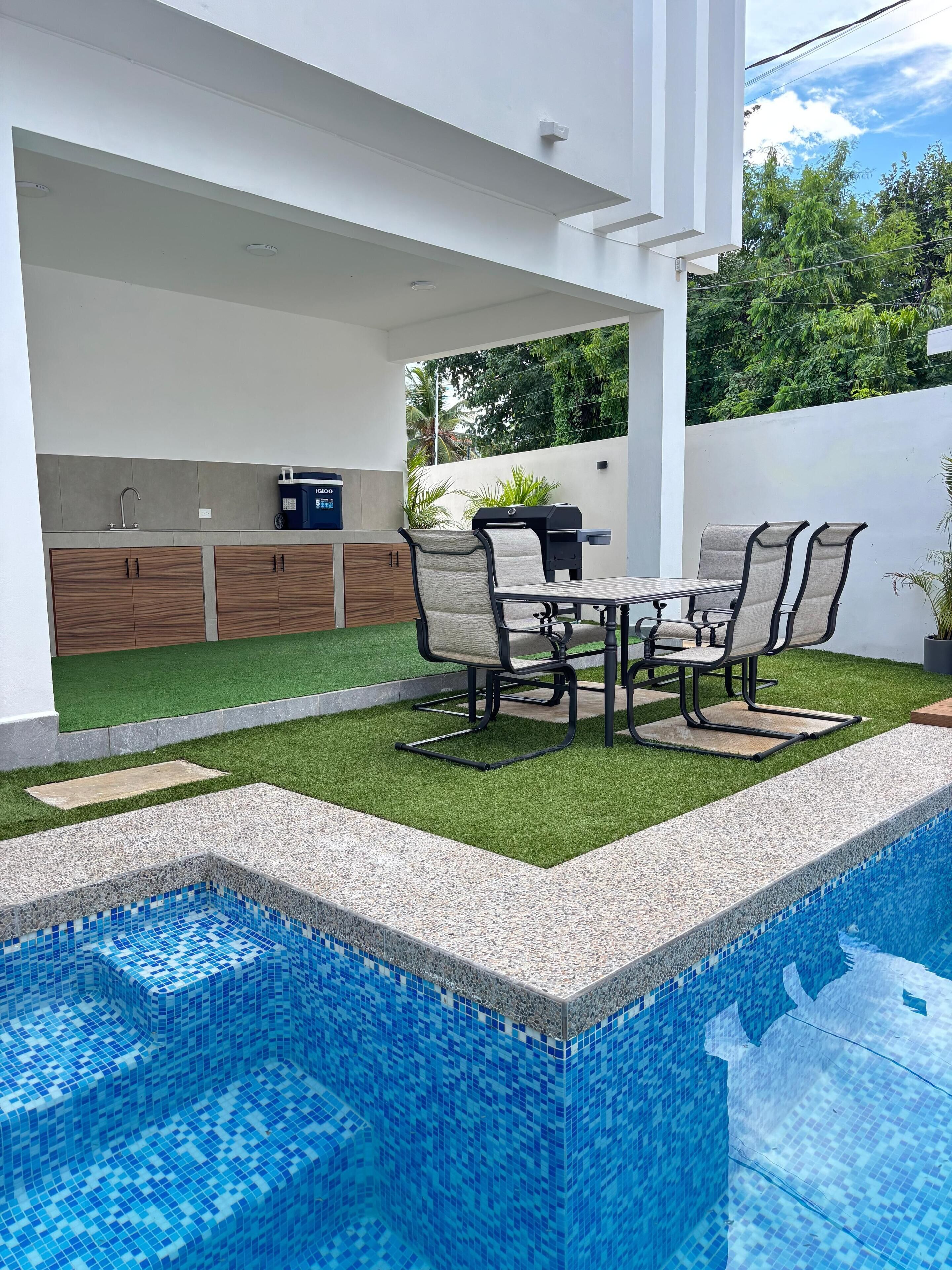 Una piscina al aire libre, sombrillas, sillones reclinables de piscina