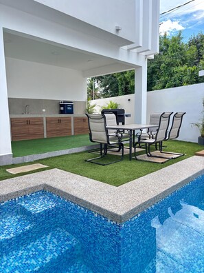 Una piscina al aire libre, sombrillas, sillones reclinables de piscina