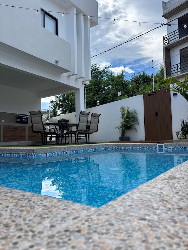 Una piscina al aire libre, sombrillas, sillones reclinables de piscina
