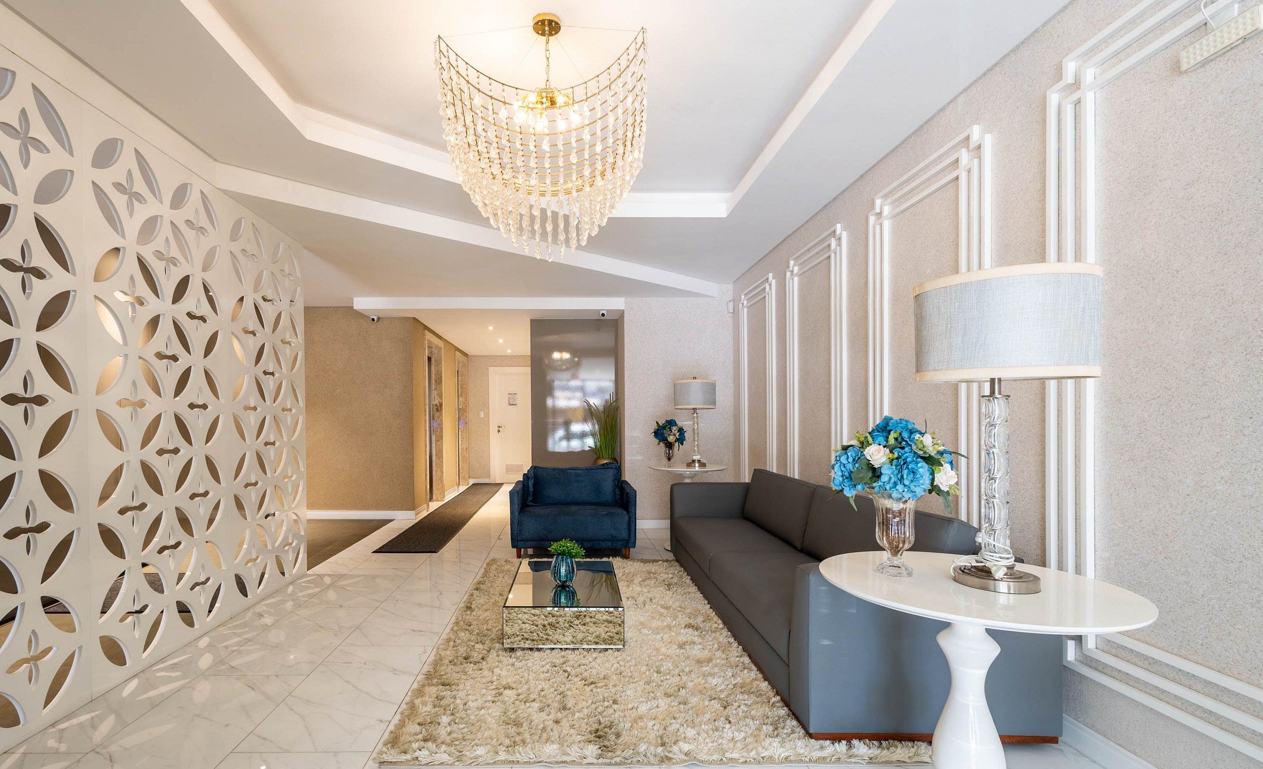A modern living room with a chandelier, a sofa, a coffee table, and a decorative vase.