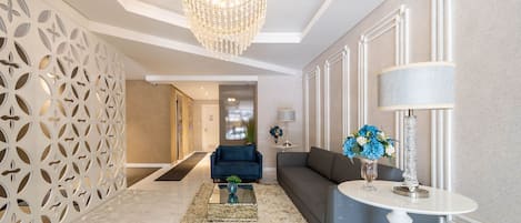 A modern living room with a chandelier, a sofa, a coffee table, and a decorative vase.