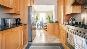 A modern kitchen with wooden cabinets, a stainless steel stove, and a refrigerator.