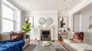 A living room with two sofas, a coffee table, a fireplace, and artwork on the walls.