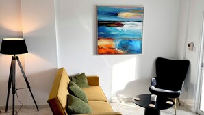 Ein modernes Wohnzimmer mit einer Couch, einem schwarzen Sessel, einer Stehlampe und einem Deckenventilator.