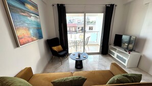 Ein modernes Wohnzimmer mit einer Couch, einem Sessel, einem runden Tisch und einem Fernseher.