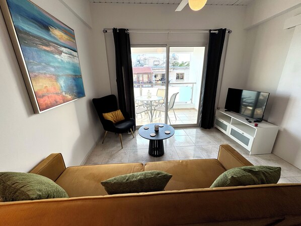 A modern living room with a sofa, a chair, a round table, and a TV.