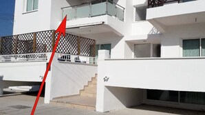 Ein modernes, zweistöckiges Gebäude mit weißer Fassade, einem Balkon im oberen Geschoss und einer Treppe zum Eingang.