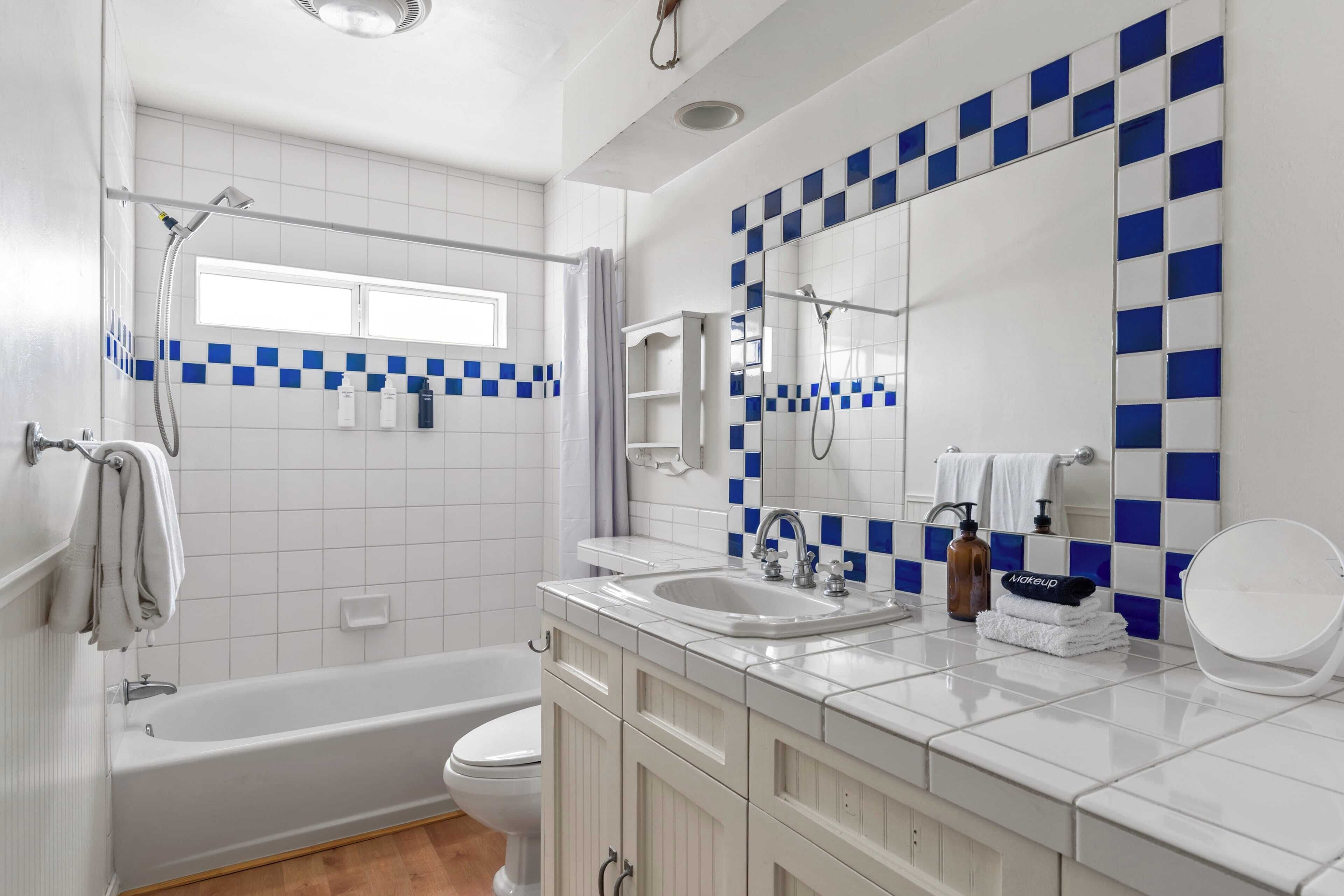 Une salle de bain avec une baignoire, des toilettes, un lavabo et un grand miroir.