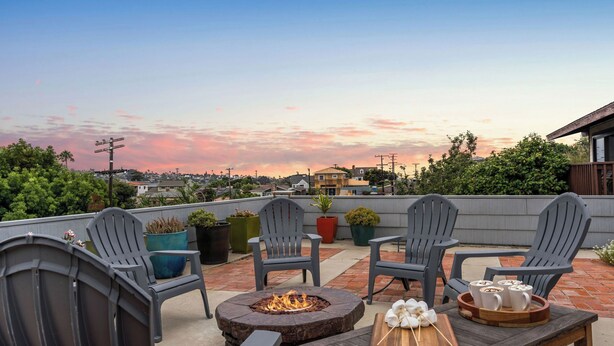A rooftop patio with four Adirondack chairs, a fire pit, and a table with mugs and marshmallows. - Point Loma Home w/ Putting Green, Firepit + Game Room & Beach Access Zola Street by Avantstay (San Diego)