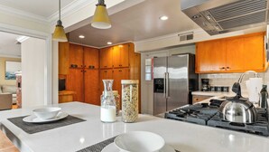 A modern kitchen with wooden cabinets, a stainless steel refrigerator, and a gas stove. - Point Loma Home w/ Putting Green, Firepit + Game Room & Beach Access Zola Street by Avantstay (San Diego)