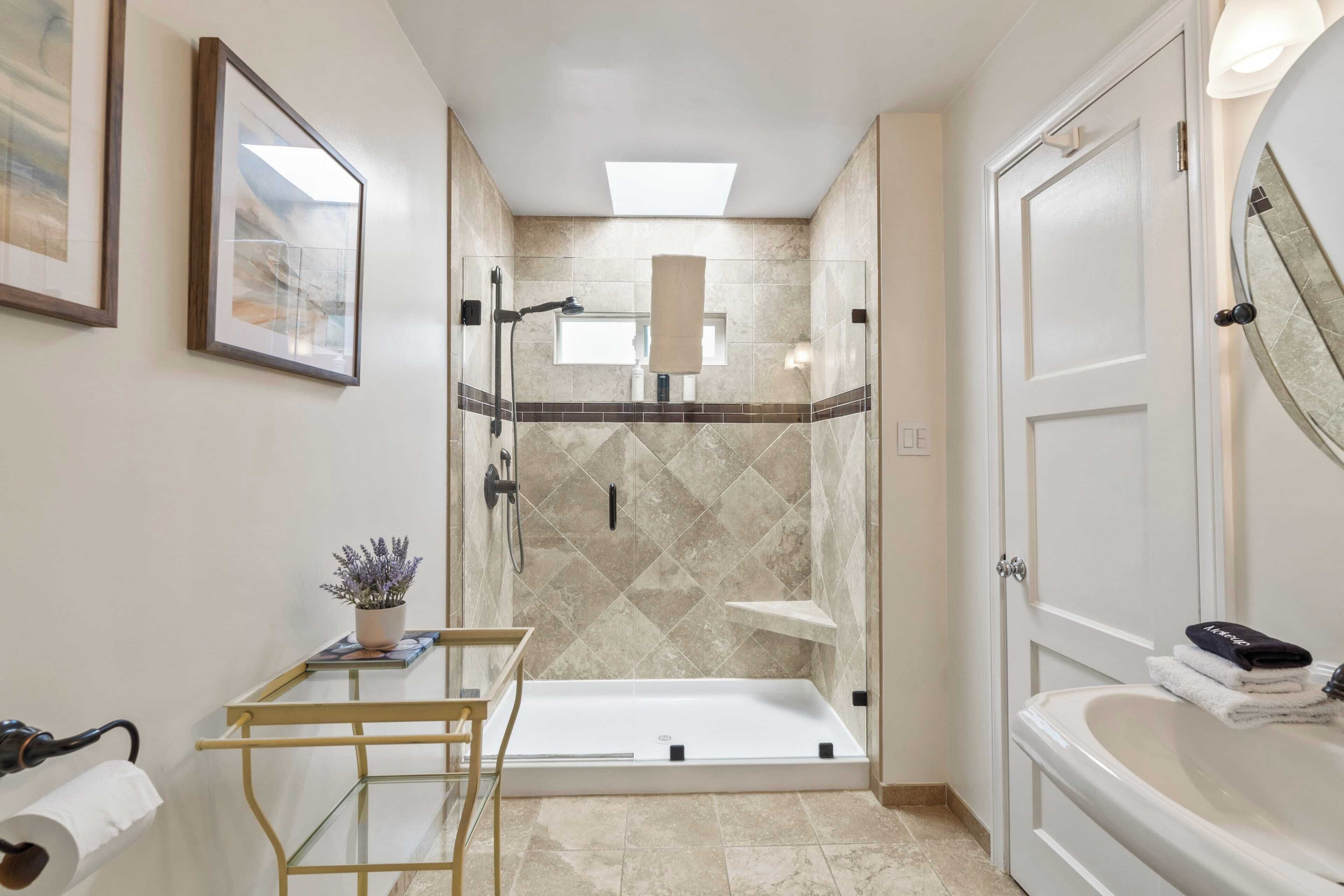 A modern bathroom with a glass-enclosed shower, a bathtub, and a vanity with a mirror.