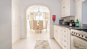 A modern kitchen with white cabinetry, a built-in microwave, and a gas stove. - The Belgravia Townhouse — Grand 8‑Guest Home (London)