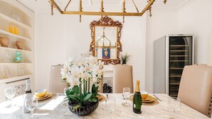 A dining area with a marble table, white chairs, a chandelier, a mirror, and a wine rack. - The Belgravia Townhouse — Grand 8‑Guest Home (London)