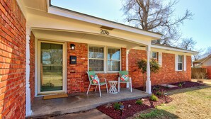 A brick house with a porch, two chairs, and a small table.