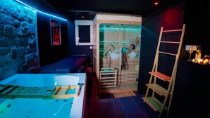 A room with a massage chair, a small table with a bottle, and a wooden ladder. - La Cachette Secrete - Love Room Caen (Caen)
