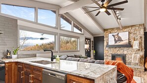 A modern kitchen with a large island, built-in appliances, and a stone fireplace.