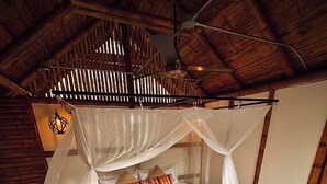 Ein Einzelbett mit Baldachin, einem Holzkopfstück und gemusterten Kissen.