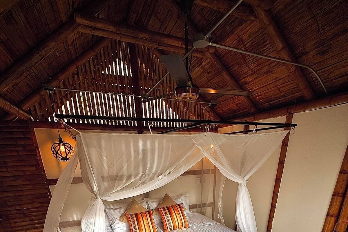Ein Einzelbett mit Baldachin, einem Holzkopfstück und gemusterten Kissen.