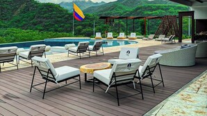 Eine Terrasse mit Liegestühlen, einem Pool und Blick auf Berge.