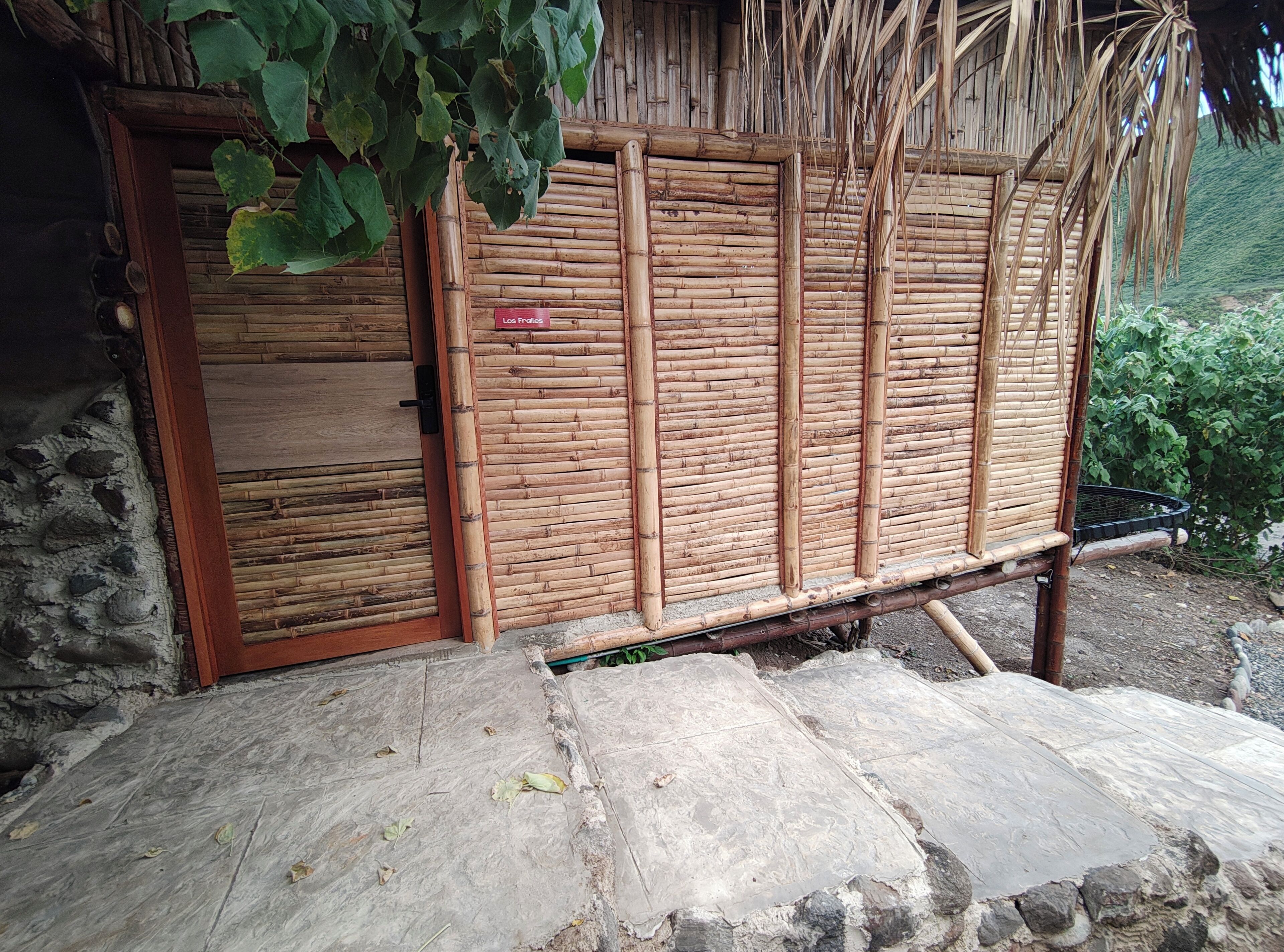 Una estructura de bambú con una puerta, un letrero que dice "Lot Fodder" y un piso de piedra.