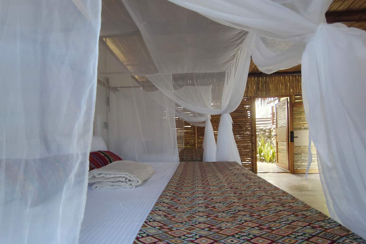 Ein Zimmer mit einem Bett unter einem Baldachin, einem gemusterten Teppich und einer Holzwand.