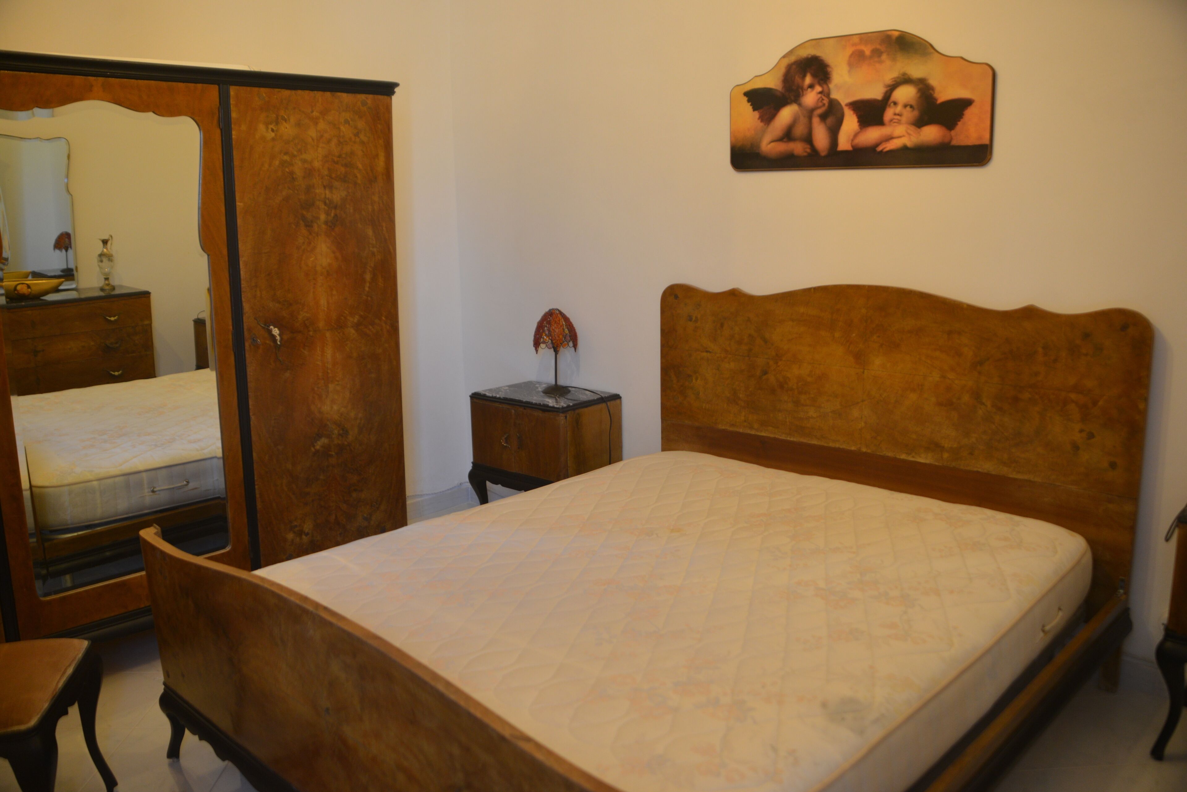 A bedroom with a wooden bed, a nightstand, a dresser, and a mirror.