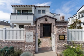 Una casa de dos pisos con fachada de ladrillo, una puerta principal negra y un buzón.