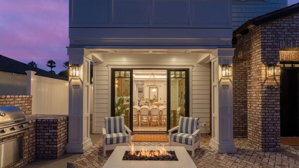 Eine Terrasse im Freien mit Feuerstelle, Sitzgelegenheiten und Grill.