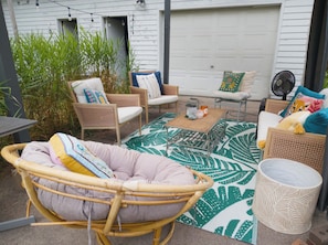 A patio area with wicker furniture, a patterned rug, and a fan.