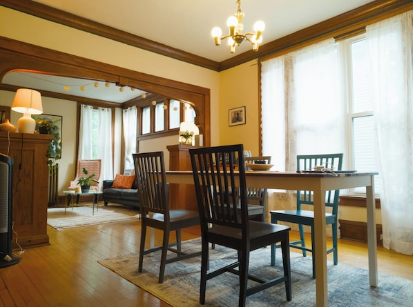 A dining area with a wooden table, four chairs, and a chandelier.