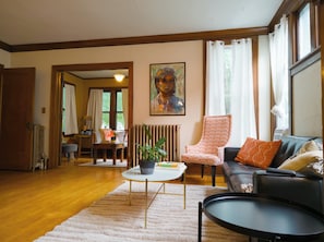 A living room with a sofa, armchair, and a coffee table with a plant.