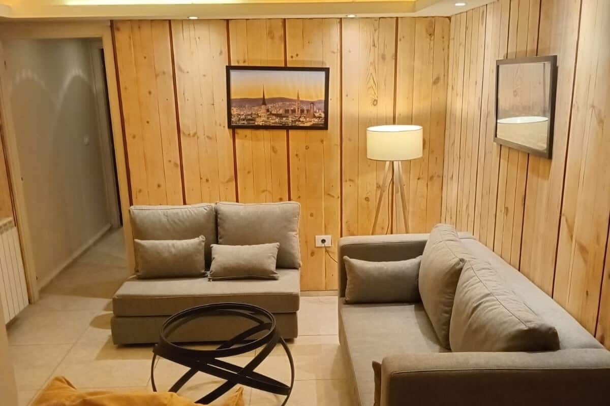 A modern living room with wooden panel walls, a sofa set, a round coffee table, and a floor lamp.