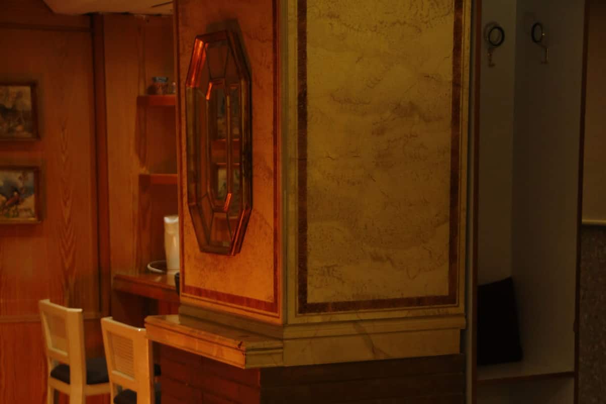 A room with a sofa, a chair, a small table, a fireplace, and a refrigerator.