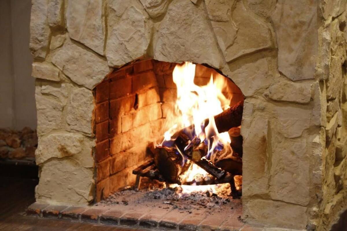 A stone fireplace with a fire burning inside.