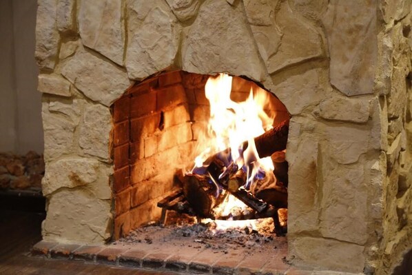 A stone fireplace with a fire burning inside.