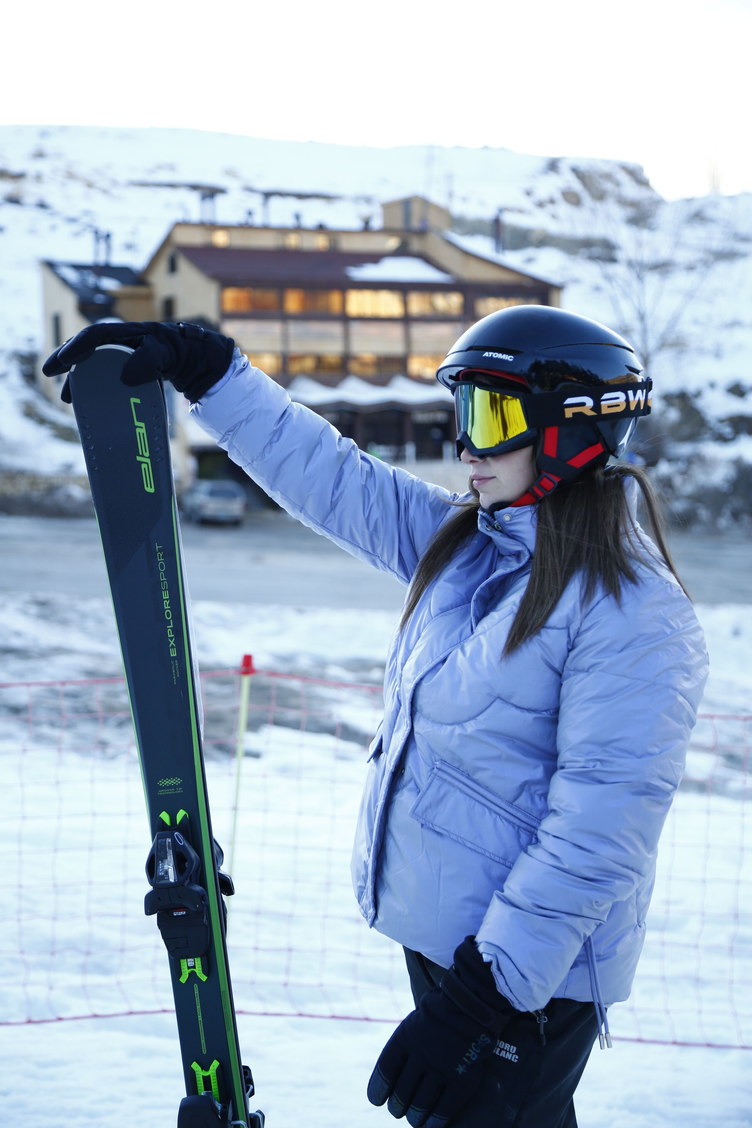 A person holding skis with a building in the background.