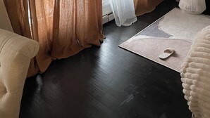 Ein Zimmer mit dunklem Holzboden, einer Couch, einem weißen Teppich und einer TV-Konsole mit Dekoration.