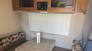 A compact RV interior with a kitchenette, a dining table, and a seating area. - Cozy Vegas Bunkhouse RV (Las Vegas)