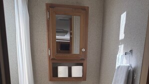 A small bathroom with a toilet, a mirror, a towel rack, and a trash bin. - Cozy Vegas Bunkhouse RV (Las Vegas)