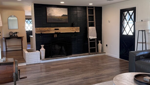 A spacious living room with a fireplace, wooden flooring, and a large window. - Spacious 4-bedroom house in charming Ephrata (Ephrata)