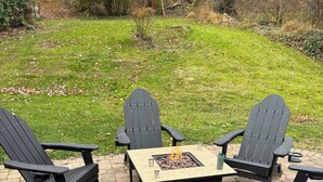 A patio area with four Adirondack chairs and a square table with a fire pit in the center. - Spacious 4-bedroom house in charming Ephrata (Ephrata)