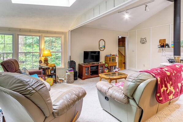 A spacious living room with leather sofas, a television, and a bookshelf. - Creekside Family Home in Cleveland: Stay & Play! (Cleveland)
