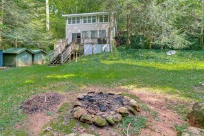 A cabin with a deck and stairs, surrounded by trees and a fire pit in the yard. - Creekside Family Home in Cleveland: Stay & Play! (Cleveland)