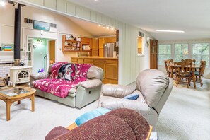 A cozy living room with a leather sofa, a glass coffee table, and a dining area with wooden chairs. - Creekside Family Home in Cleveland: Stay & Play! (Cleveland)
