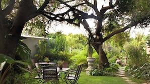 Ein Garten mit Tisch und Stühlen, umgeben von verschiedenen Pflanzen und Bäumen.