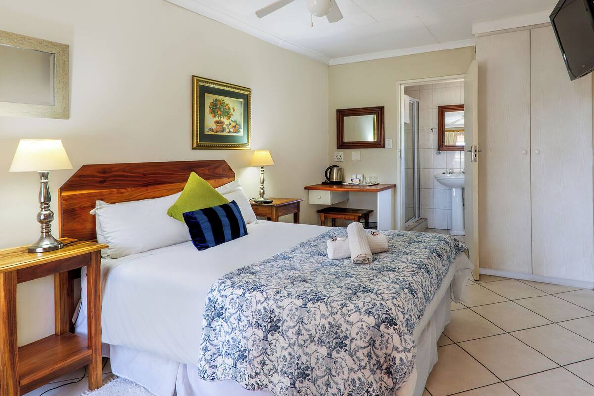 Une chambre d’hôtel comprenant un lit, des tables de chevet, un bureau, une douche et un téléviseur.