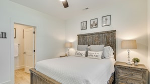 A bedroom with a large bed, wooden headboard, bedside tables, and a door leading to another room. - 2 Mi to UT: Modern Retreat w/ Covered Porch (Knoxville)