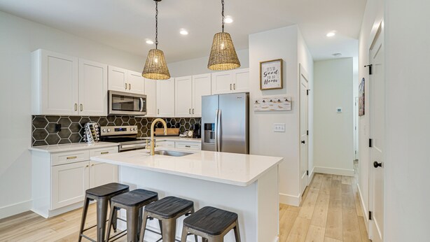 A modern kitchen with white cabinets, a stainless steel refrigerator, a microwave, and a large island with bar stools. - 2 Mi to UT: Modern Retreat w/ Covered Porch (Knoxville)