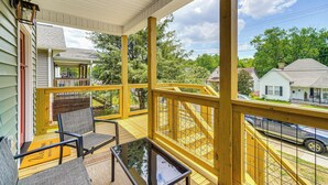 A covered porch with a wooden railing, outdoor seating, and a view of the neighborhood. - 2 Mi to UT: Modern Retreat w/ Covered Porch (Knoxville)
