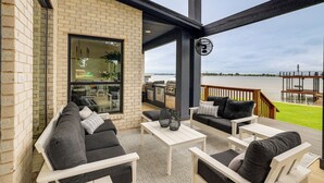 Une terrasse extérieure couverte, avec un mur en briques, une table blanche et des meubles noirs et blancs.